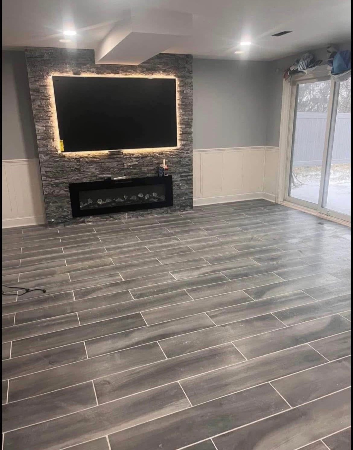 Finished media room with tile floor and fireplace feature wall