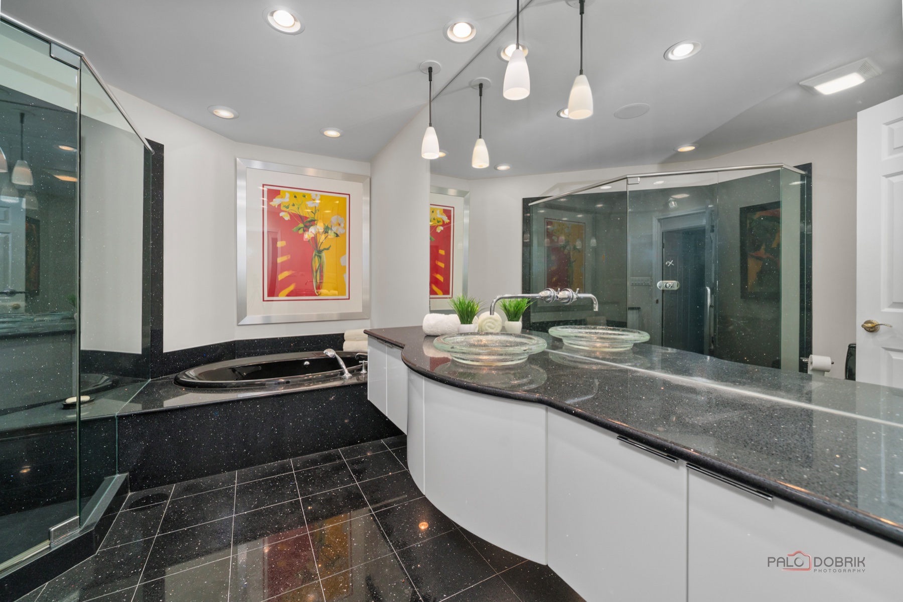 Finished bathroom renovation with dark tile, glass shower, and double vanity