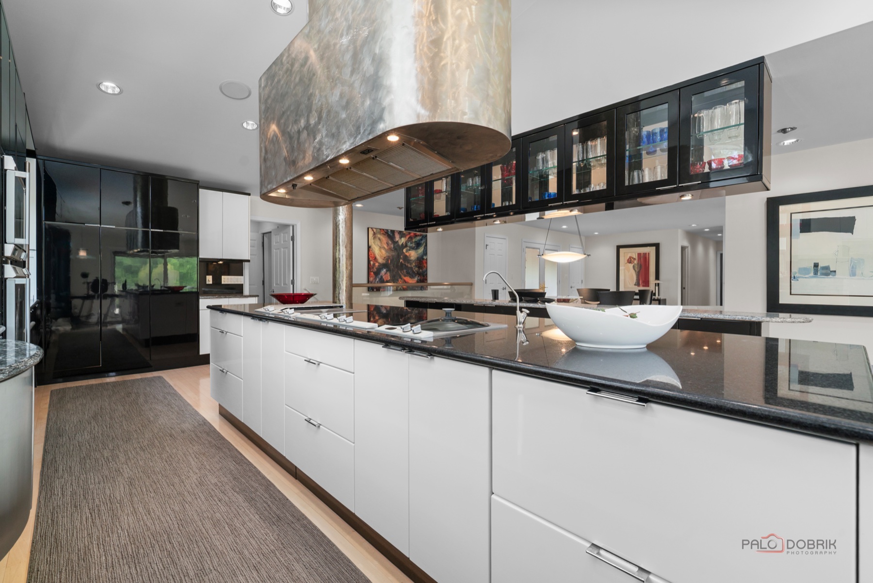 Kitchen renovation with black and white cabinetry and custom range hood