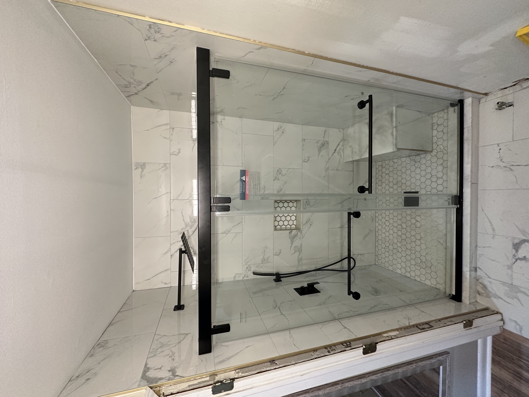Finished glass shower with marble tile and black hardware